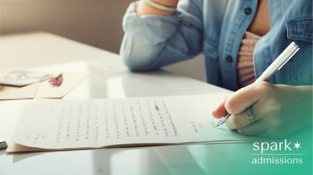 Close-up of a student writing a letter by hand with a pen at a desk