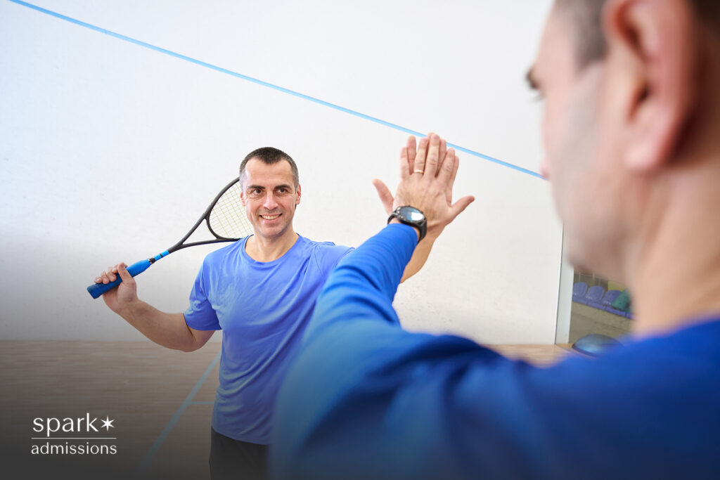 Squash player smiling and giving a high five after a match