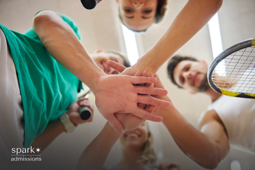 Group of squash players stacking hands in a team huddle on the court