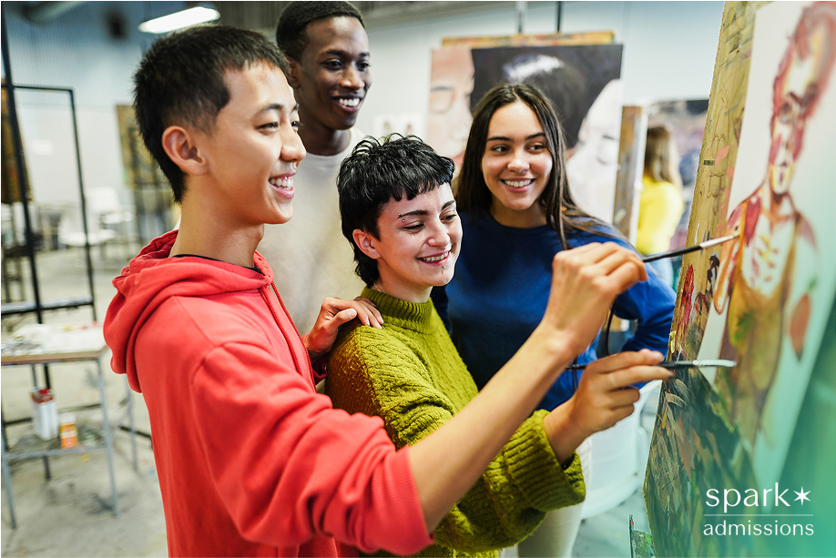 Four students collaborating on a painting in an art classroom