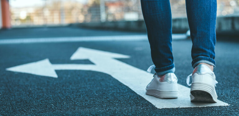 A woman walking on a path with an arrow pointing both forward and to the left