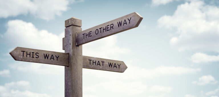 Wooden signpost with multiple arrows pointing in different directions labeled “This Way,” “That Way,” and “The Other Way.”