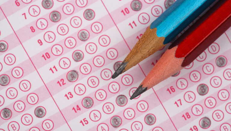 Two sharpened pencils rest on a multiple-choice answer sheet filled with darkened bubbles