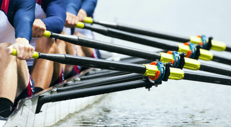 Close-up of a rowing team synchronizing their strokes on the water during a race