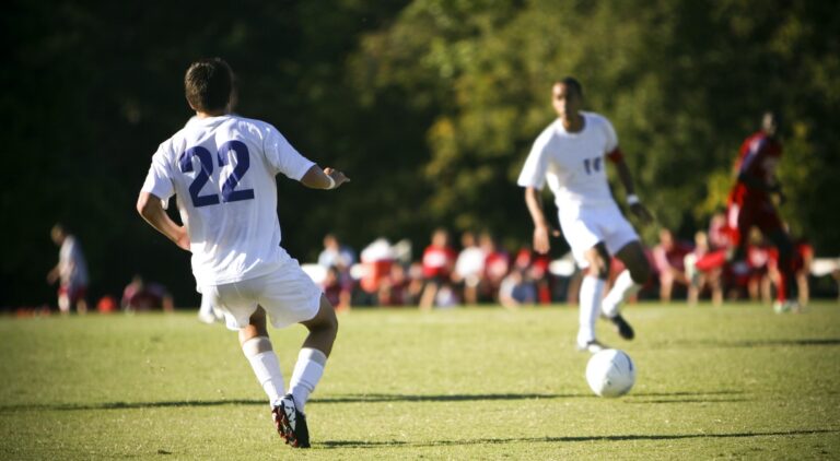 Two soccer teammates passing the ball in the middle of a soccer match