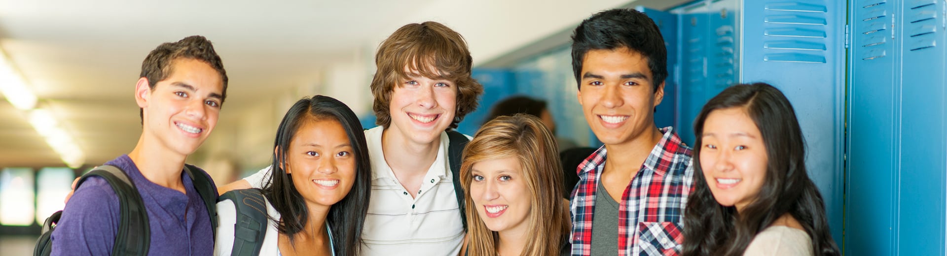 A group of smiling high school students standing by lockers