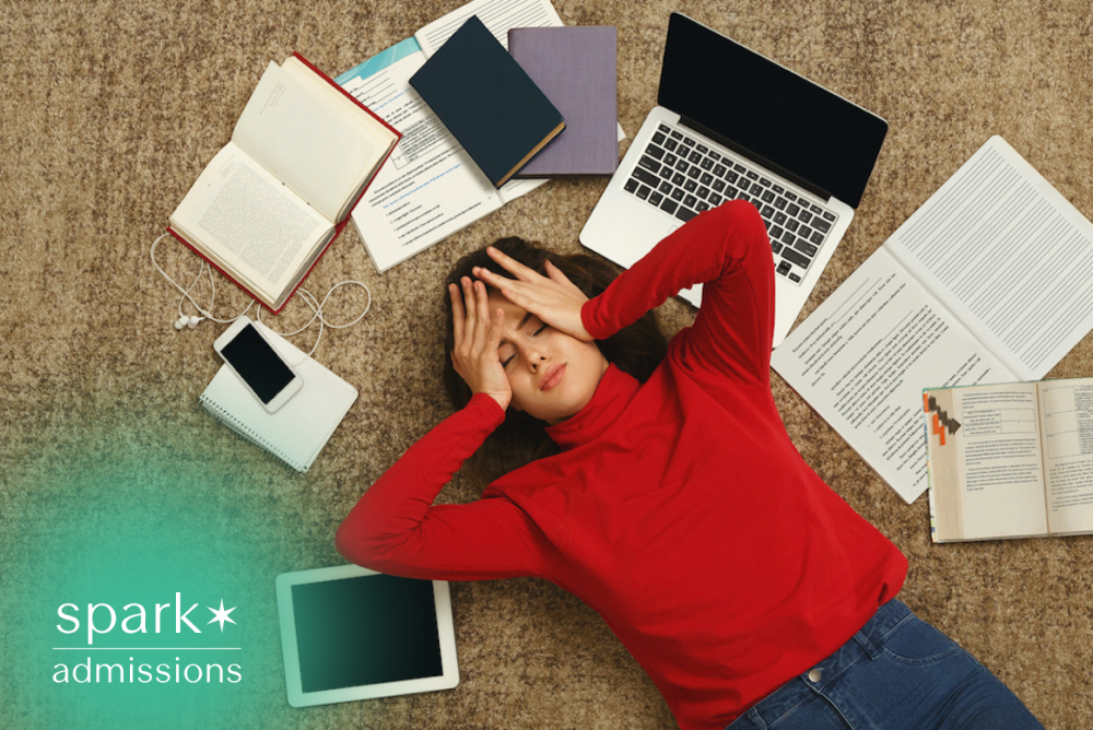 Overwhelmed college student lying among books, laptop, and notes while studying for exams.