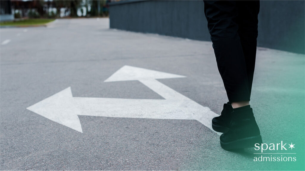 A student walking at a fork in the road with white arrows painted on pavement pointing left and right