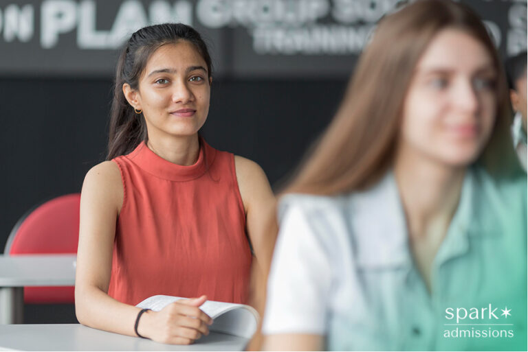 High school student in classroom reviewing materials during college admissions preparation