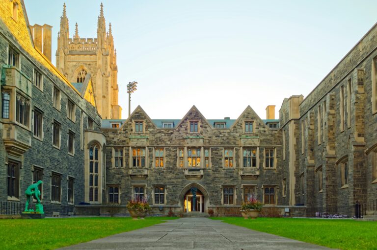 Courtyard of a historic university building with gothic architecture and green lawn