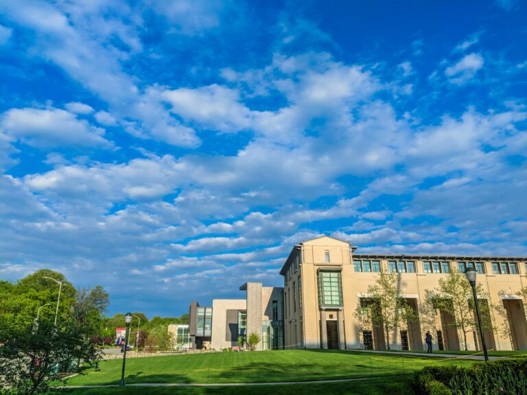 Carnegie Mellon University’s campus with a modern building, open green space, and a dramatic cloudy blue sky, emphasizing innovation and open learning environments