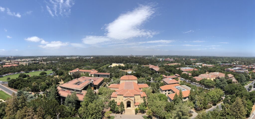 Panoramic view of Stanford University campus with red-roof buildings surrounded by greenery