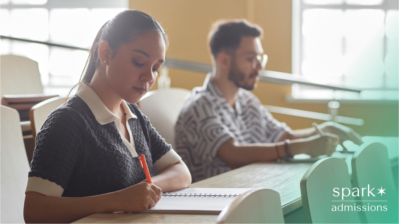 College students taking notes during class in a lecture hall with natural light