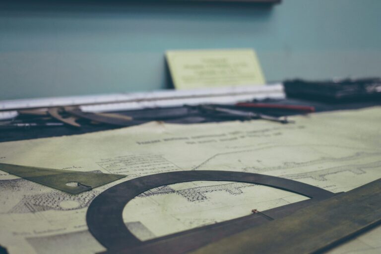 Drafting tools laid out on an old engineering blueprint in a workspace