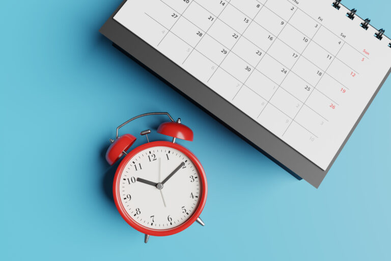 A red alarm clock next to a calendar on a blue background, showing a focus on time and planning