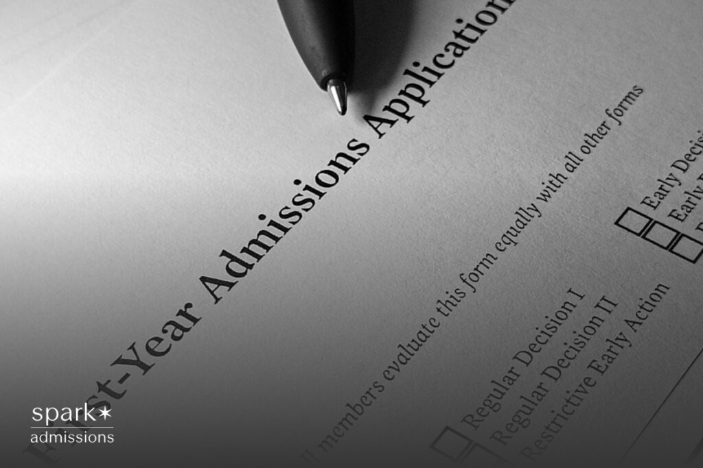 A pen rests on top of a printed first-year college admissions application with checkboxes for decision types
