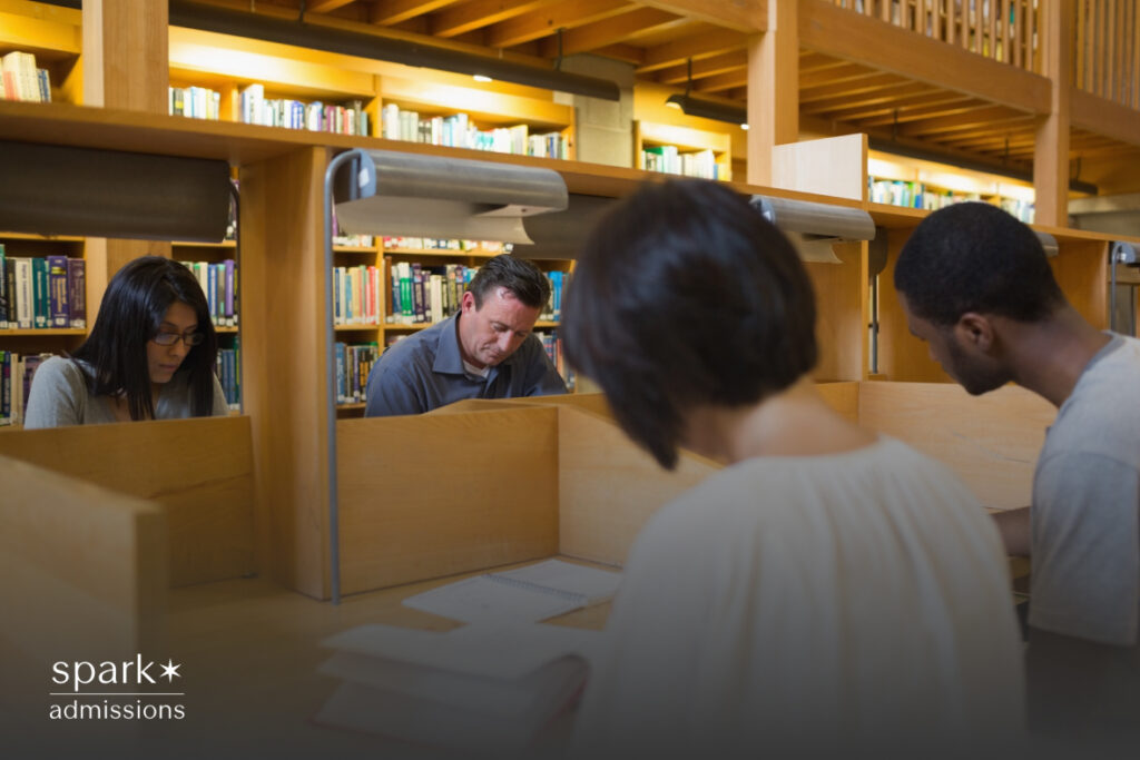 Four students focus on their work while seated in individual study carrels at a public library