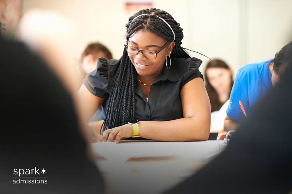 A student smiling while writing during a class or test setting