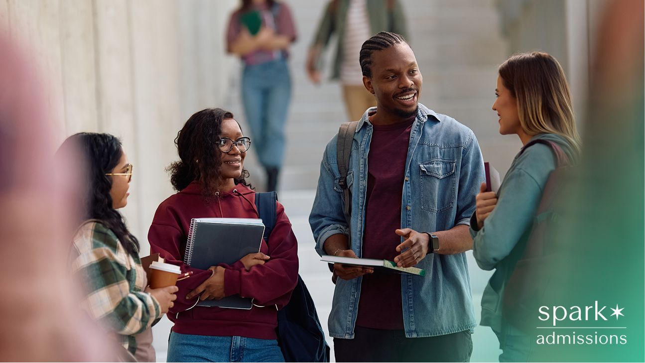 Group of diverse college students talking and smiling in a hallway, holding notebooks and coffee
