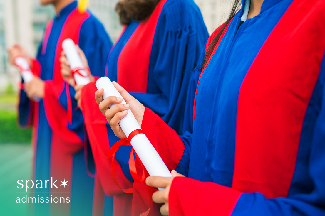 Students in blue and red graduation gowns holding diplomas wrapped with red ribbons