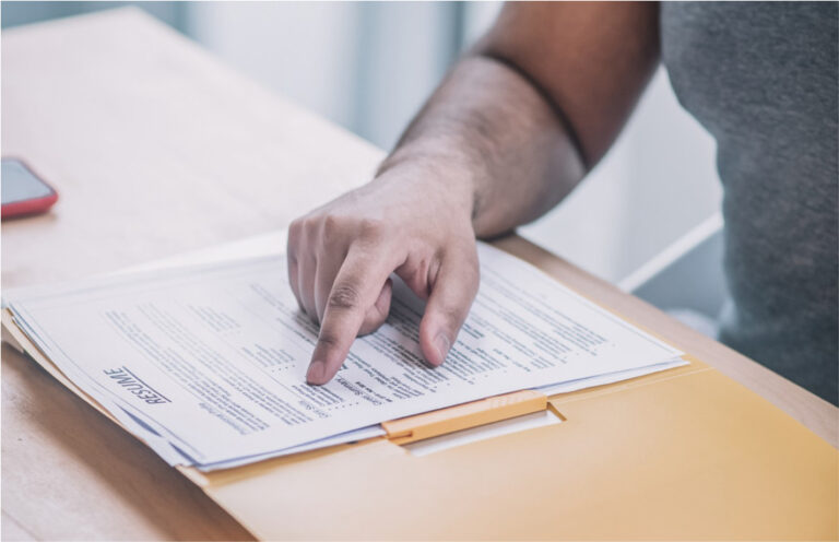 Close-up of a hand pointing at a document on a desk