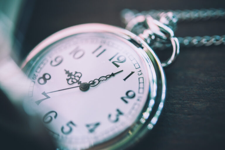 Close-up of a silver pocket watch showing the time with a blurred background