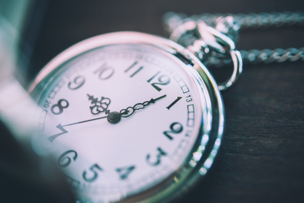 Close-up of a silver pocket watch showing the time with a blurred background