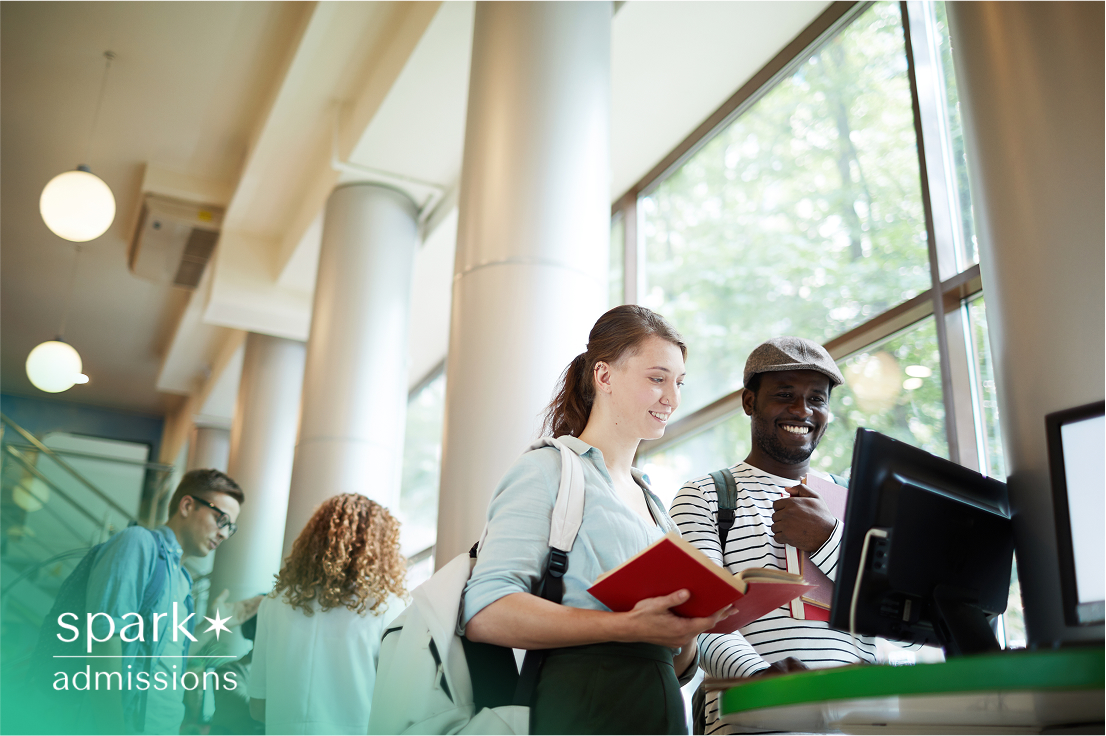 Group of students smiling and looking at a computer screen in a college building