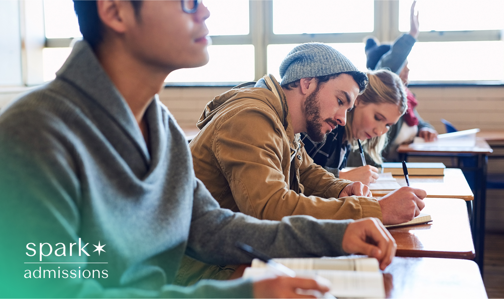 College students seated in a classroom, writing in notebooks during a lecture