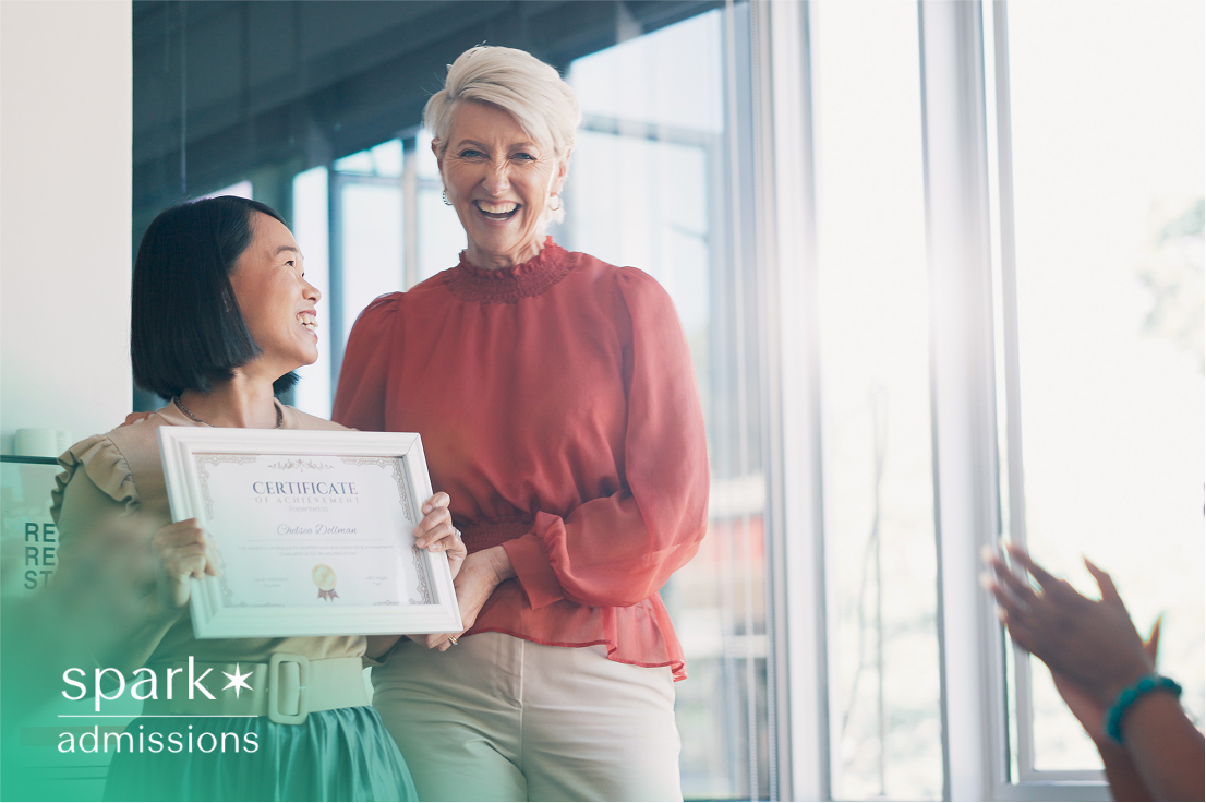 Smiling student holding a certificate with a teacher during a recognition ceremony