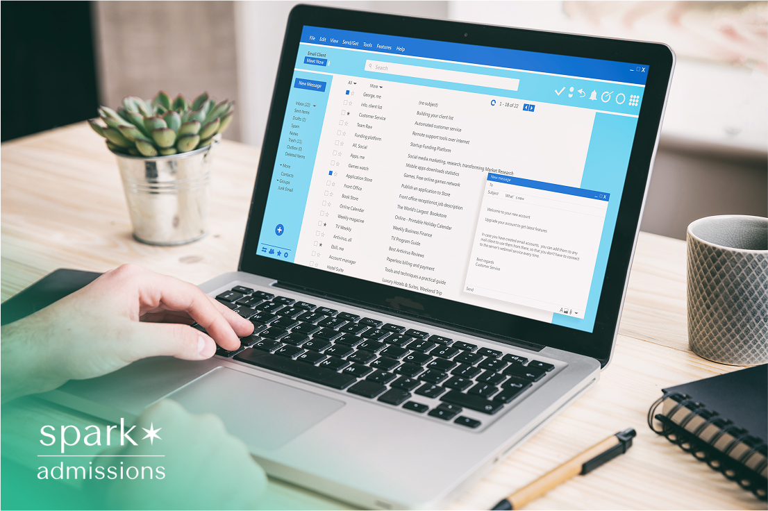 Close-up of laptop screen showing email inbox and hands typing a message at a desk