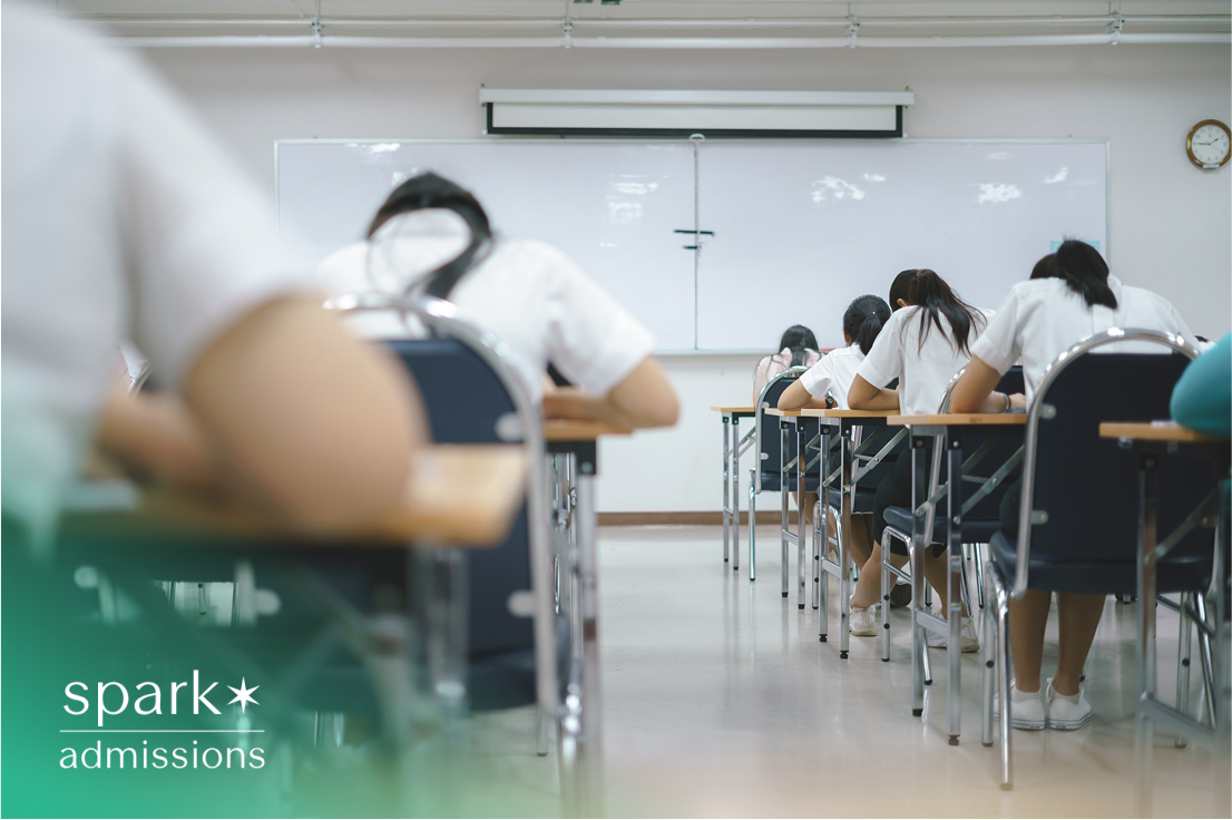 Students taking an exam in a classroom, facing the whiteboard