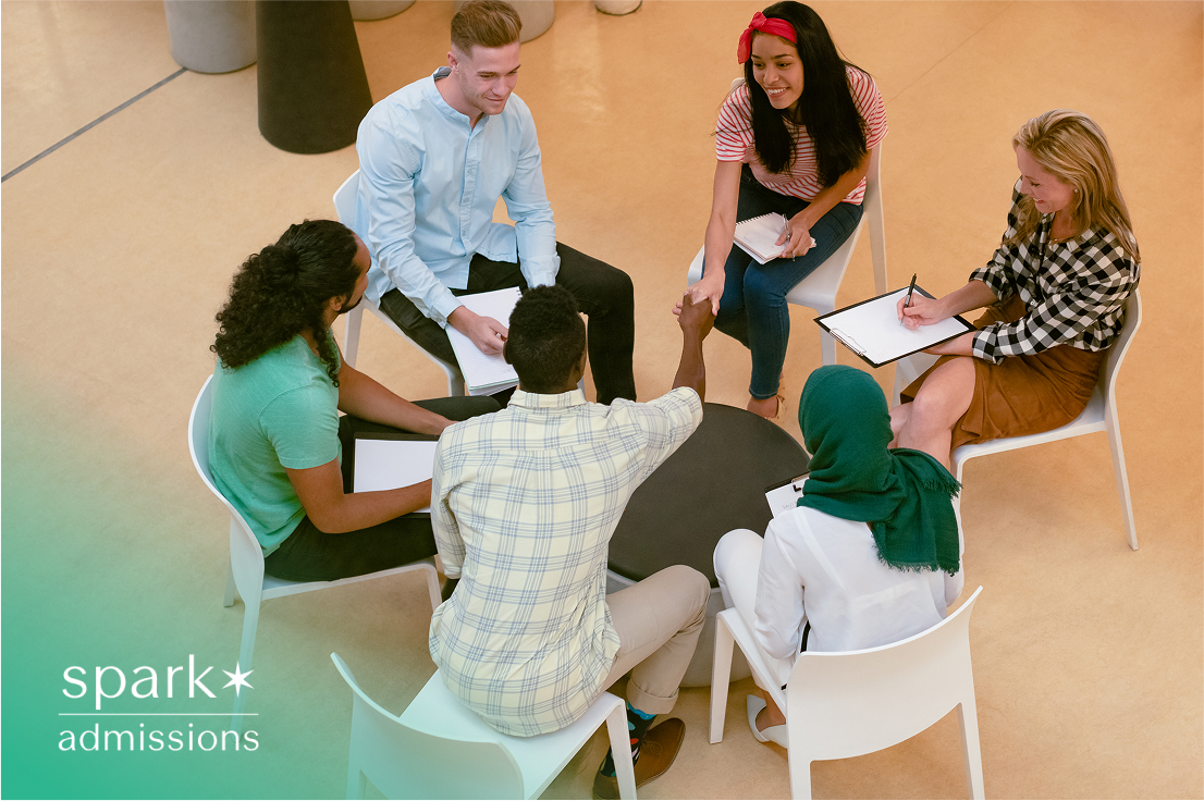 Diverse group of students sitting in a circle, discussing and taking notes during a meeting