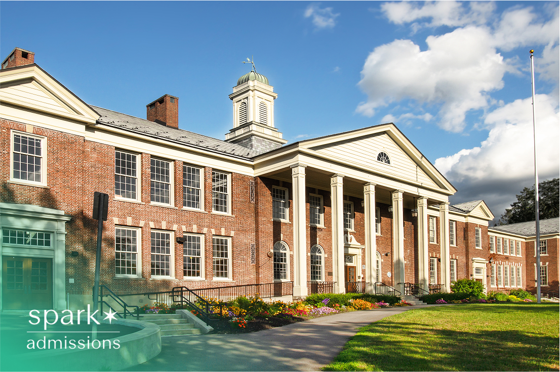 Exterior view of a large brick college building with columns and a clock tower