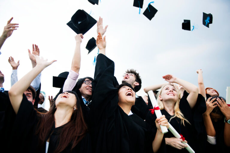 Graduates in caps and gowns celebrating by throwing their graduation hats into the air