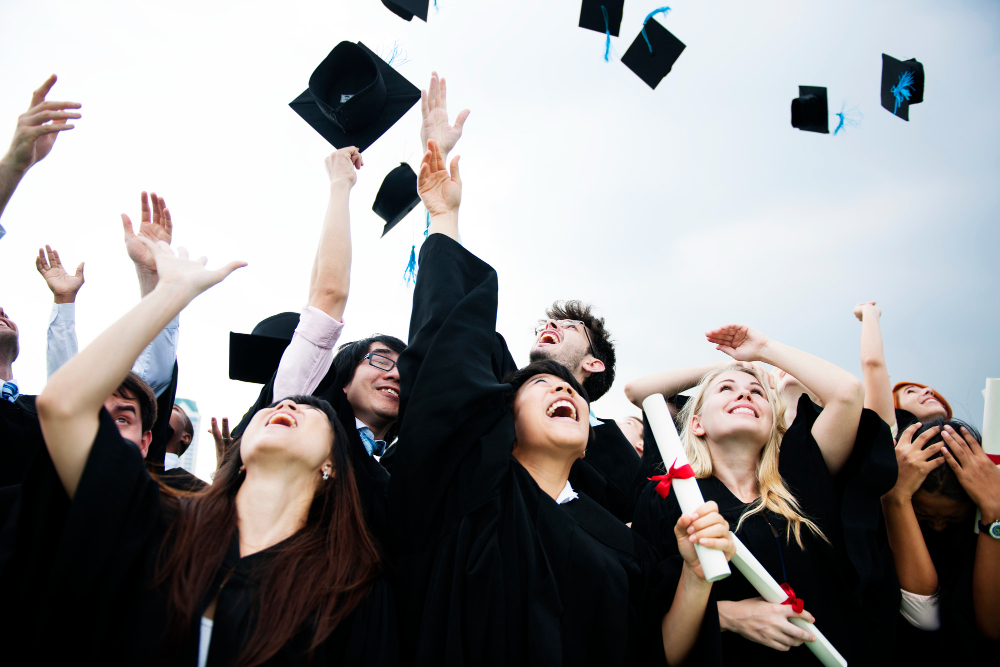 Graduates in caps and gowns celebrating by throwing their graduation hats into the air