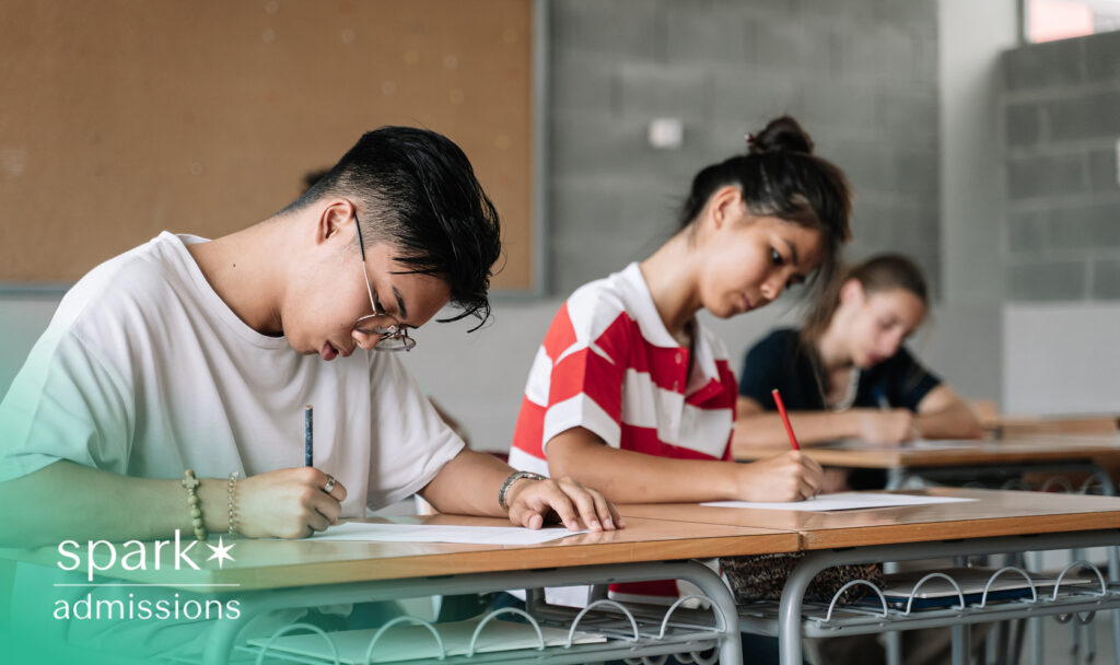 A students in a classroom sitting at desks, focused on writing during a test or assignment