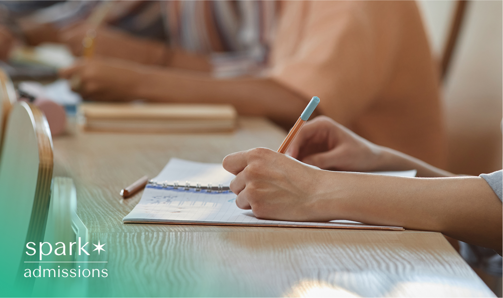 A student taking notes in a spiral notebook during class