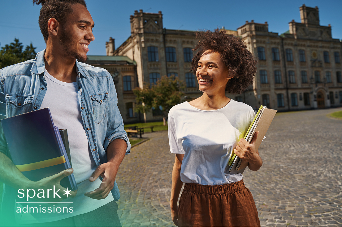 Two smiling college students walking outside on campus holding books and notebooks
