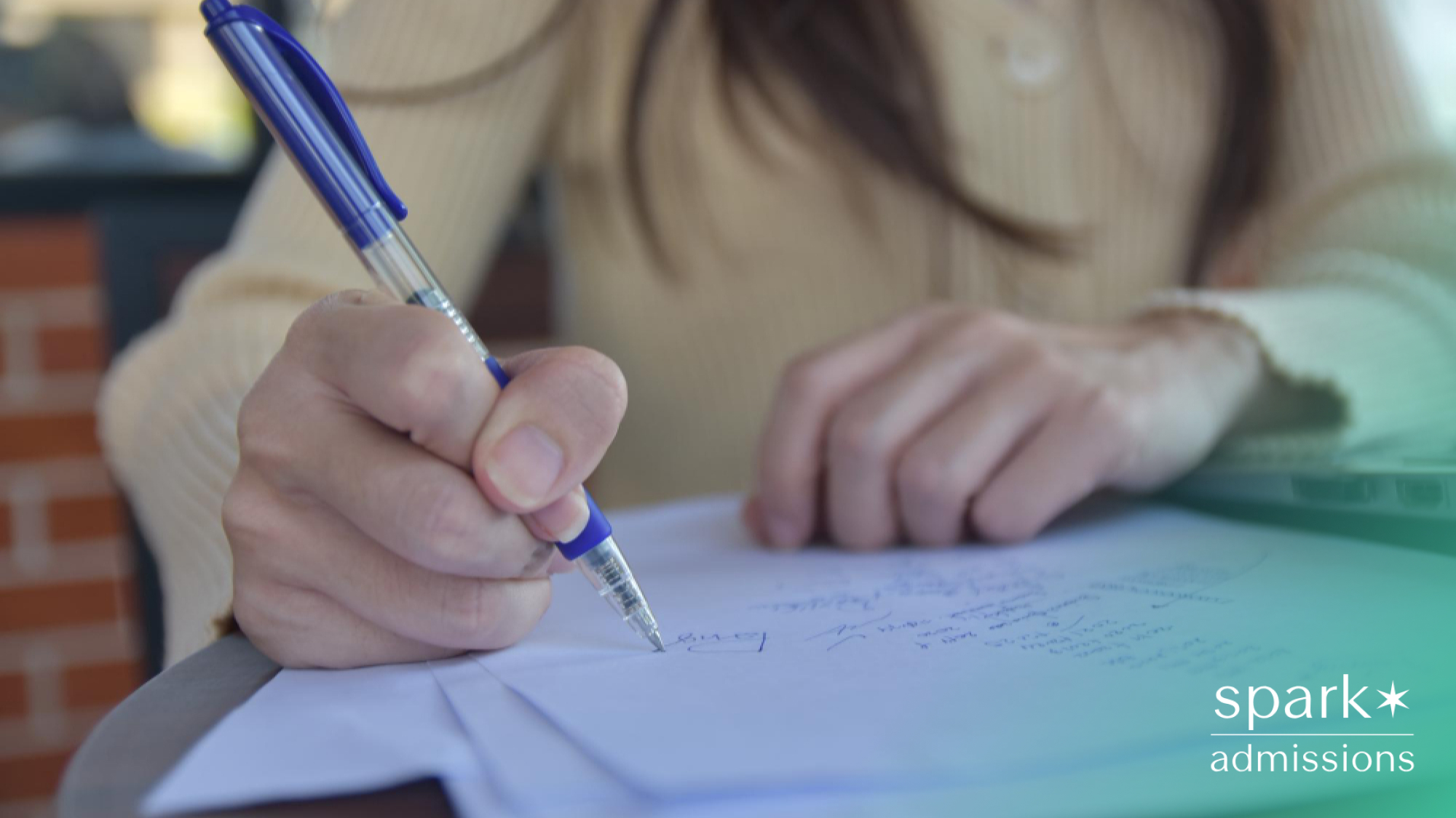 A female student writing on a sheet of paper with a blue pen at a desk
