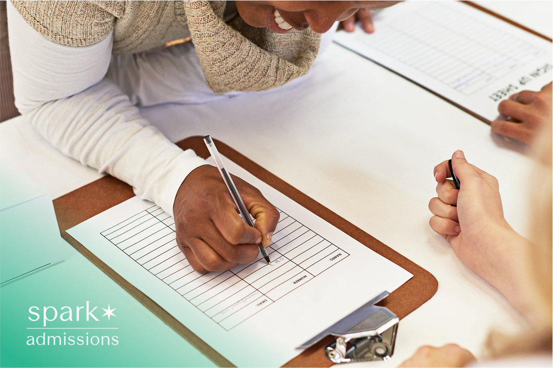 A student filling out a form on a clipboard at a registration table