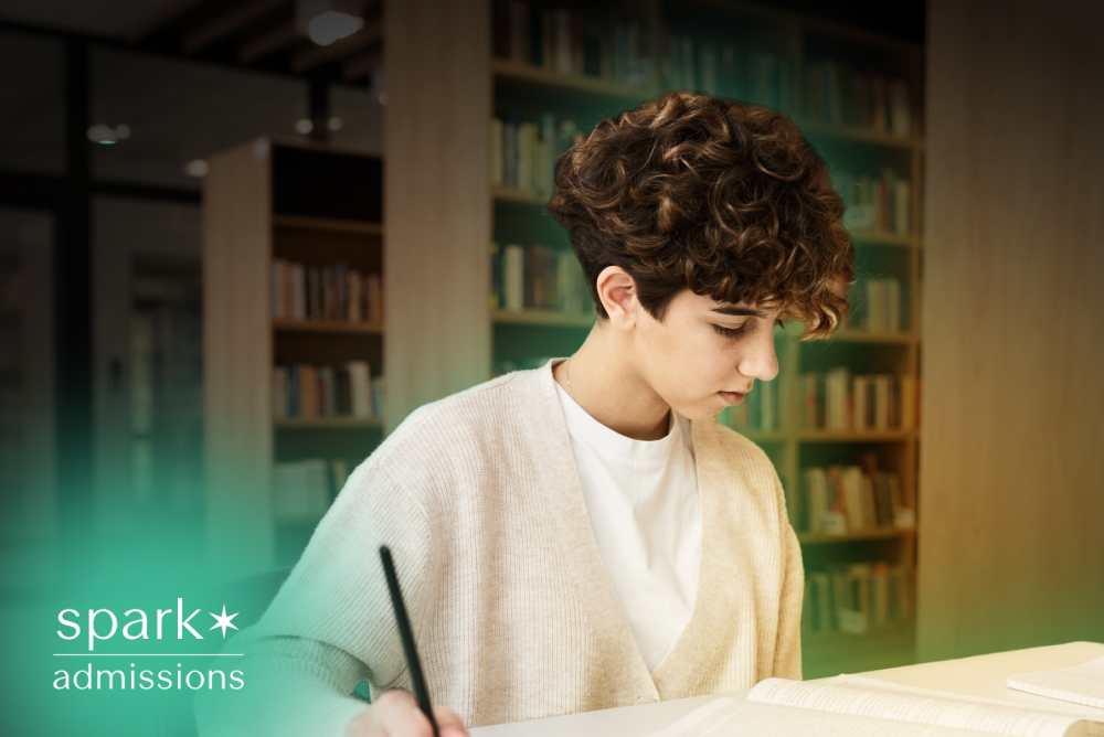 Student studying in a library while writing notes in an open book