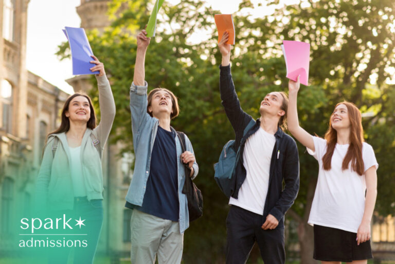 Students celebrating on campus while holding colorful folders