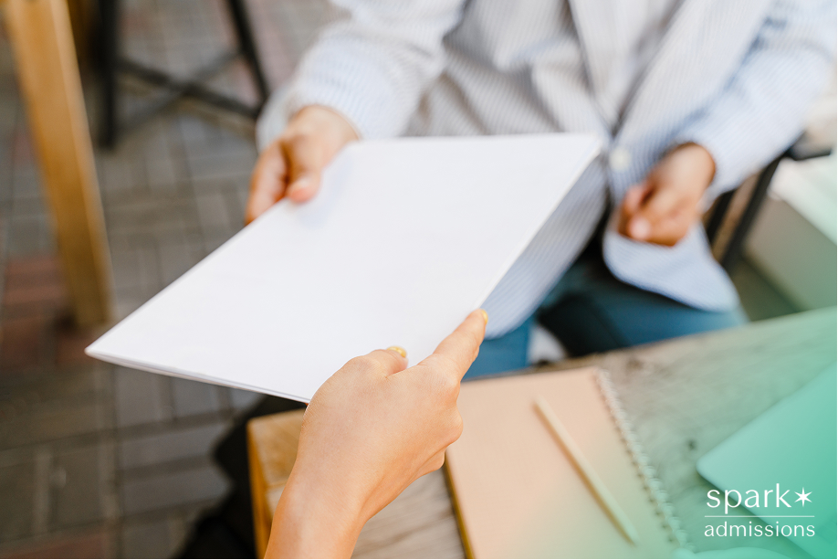 Close-up of one person handing a document to another across a table