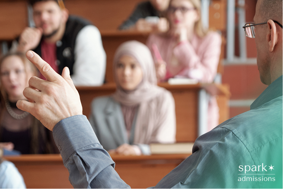 A professor gestures while teaching students seated in a lecture hall