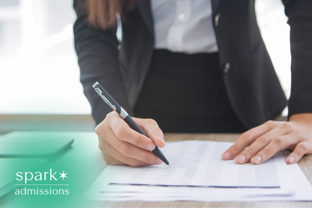 Admissions consultant reviewing application documents with a pen