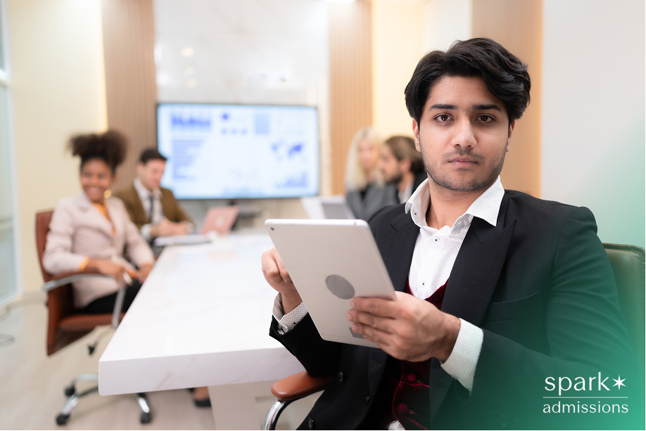 A young professional holds a tablet with a serious look in a modern office, demonstrating teamwork in the best extracurriculars for business majors