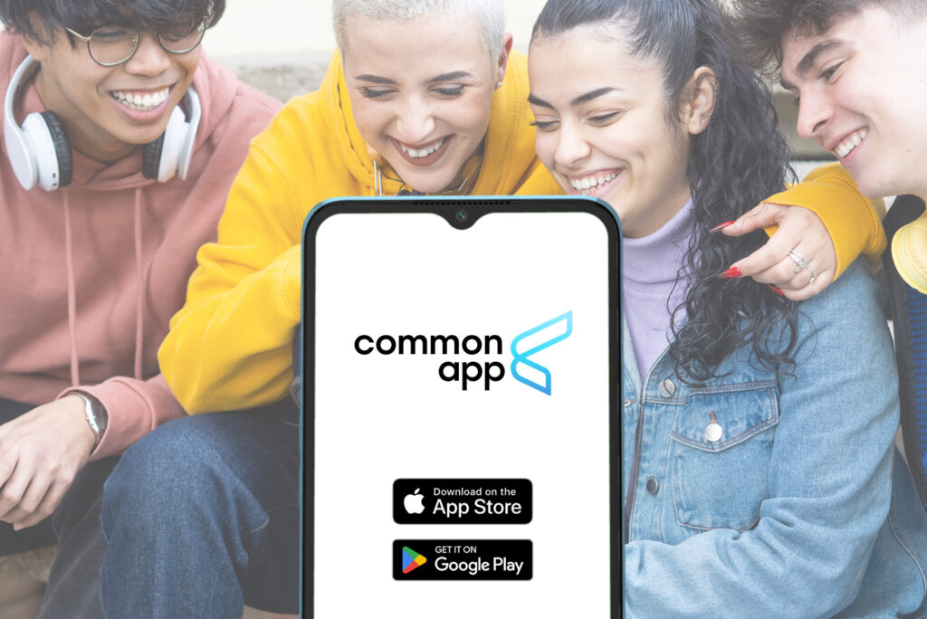 A group of students smile around a phone displaying the Common App logo and app download icons