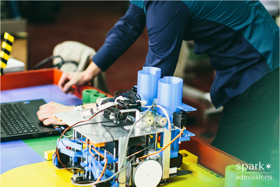 A student works on a project for engineering beside a laptop