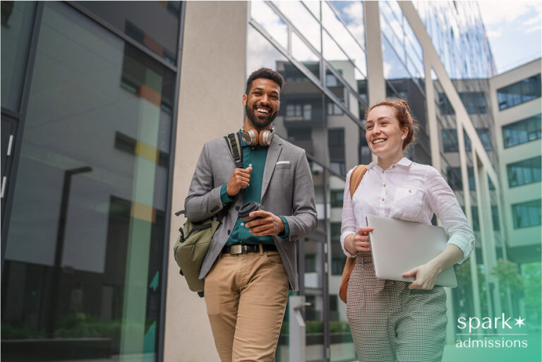 Two students smile while walking outside a modern academic building